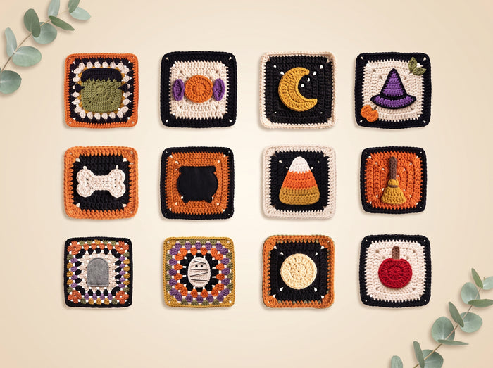 A set of 12 handmade crocheted square coasters arranged in a 3x4 grid on a light beige background with decorative eucalyptus leaves in the corners. Each coaster features a different Halloween-themed design, including a tombstone, candy corn, moon, witch hat, broom, cat, pumpkin, and other spooky motifs.