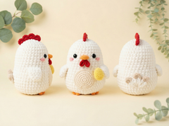 Three crocheted chicken amigurumi toys shown from different angles on a warm cream background with decorative green leaves. The chickens are white with red combs/wattles, orange beaks/feet, and small yellow accents.