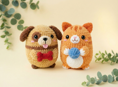 Two cute crocheted plush toys, a tan dog with a red bow tie and an orange hamster in a white vest holding a blue ball, set against a warm cream background with eucalyptus leaves.