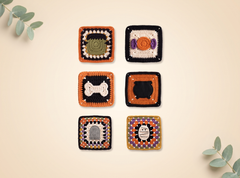 Six handmade crocheted square coasters with Halloween-themed designs, including a cat, dog, pumpkin, skull, and cat head, arranged in a grid on a beige background with decorative eucalyptus leaves.