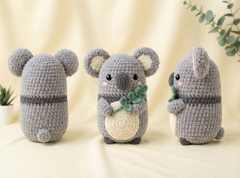 Three crocheted koala plush toys shown from different angles on a soft cream fabric background, with small potted plants in the corners.