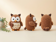 Three crocheted owl toys in brown and cream are displayed on a light beige surface against a warm beige background. The left owl faces forward holding a small brown acorn, the center owl is turned to the side, and the right owl shows the back.